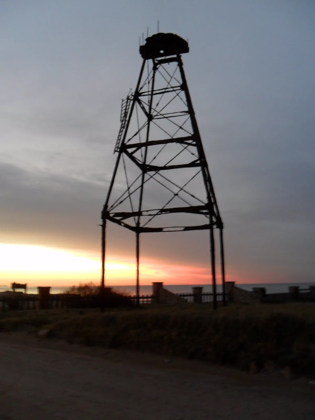 Silueta de la torre oxidada al amanecer, con la escalera de gato a un costado y la plataforma deshecha