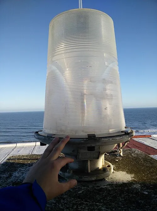 La linterna actual, un cilindro de vidrio estriado sobre una base metálica, en la azotea del Playa Club, con el mar de fondo