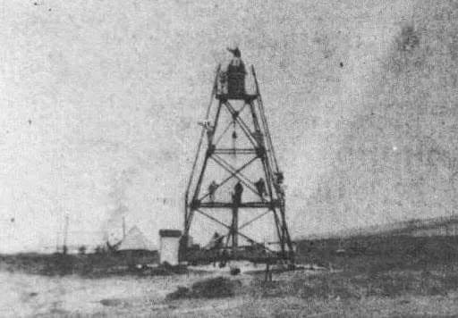 Foto antigua de la torre de hierro de la baliza, con varias personas subidas a la estructura