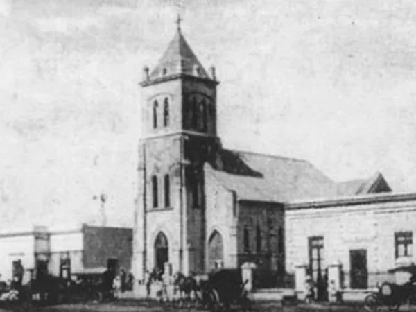 Foto antigua en blanco y negro de la iglesia con la torre rematada por una aguja en punta