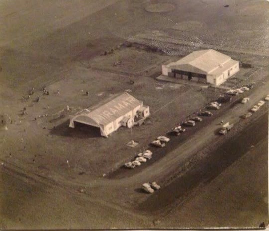 Foto aérea antigua del aeródromo de Miramar: el hangar con MIRAMAR en el techo, el segundo hangar y autos estacionados junto al camino