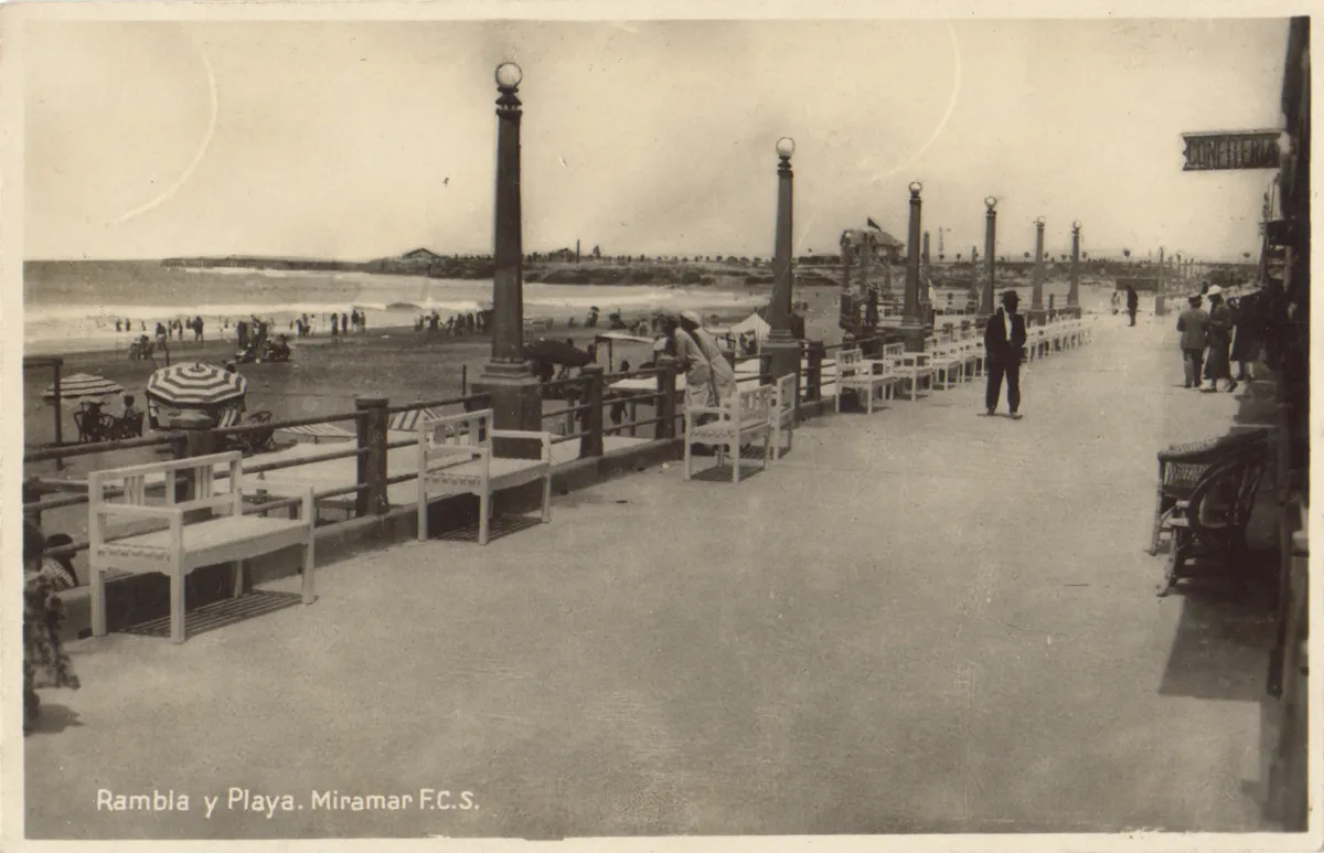 Postal Rambla y Playa, Miramar F.C.S.: el paseo de la rambla con bancos blancos contra la baranda, faroles de globo, sombrillas a rayas en la playa y el cartel de la confitería a la derecha