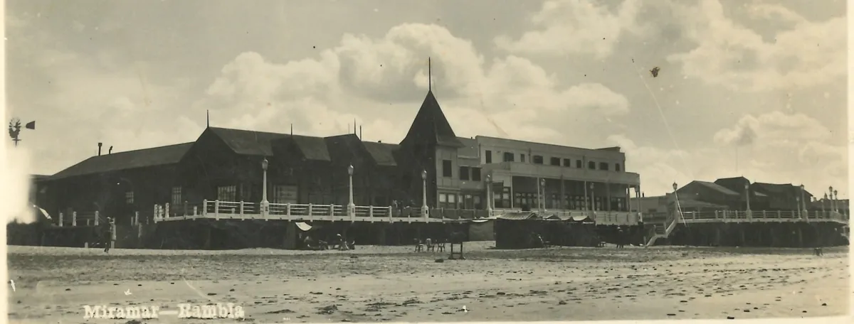 Postal de mediados de los años 40: la rambla de frente desde la playa, con un pabellón largo de madera, la torre en punta, el Playa Hotel y la plataforma con balaustrada y faroles